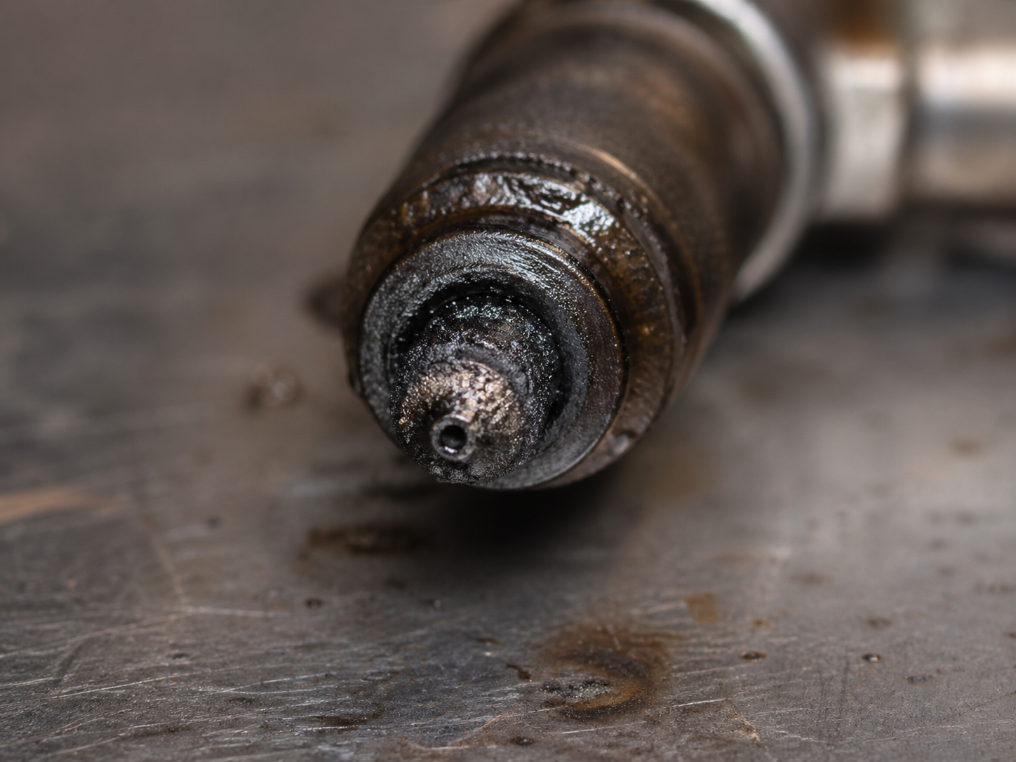 Macro de la punta de un inyector diésel con carbonilla, suciedad y depósitos adheridos en la tobera