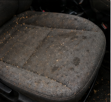 Asiento de tela automotriz con suciedad, manchas y residuos acumulados
